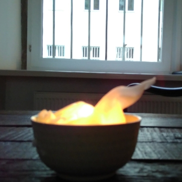 Bild zeigt eine brennende Kerzenschale auf einem Holztisch